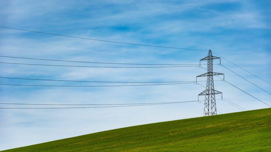 Electricity pylon in a green field against a blue sky on a summers day.