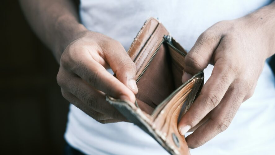 Photo showing a person's hands, opening a brown, empty wallet