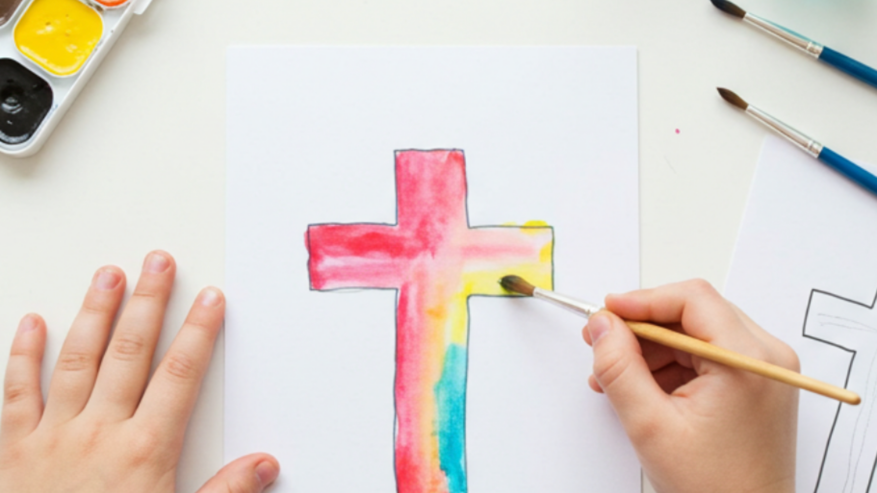 Religious Easter craft of a child painting a cross shape with watercolours