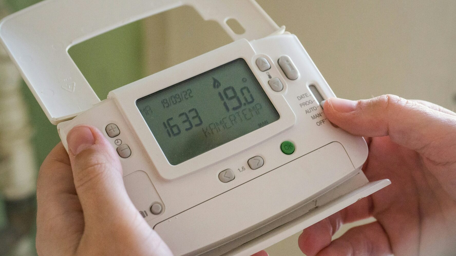 A picture showing someone holding a heating thermostat