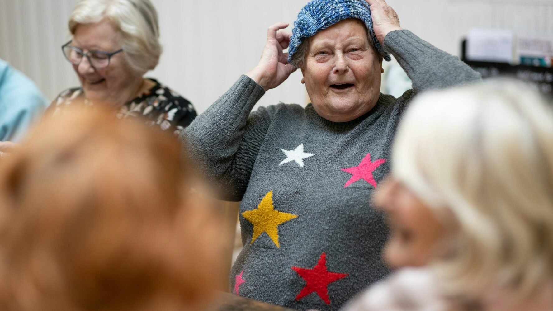 Older person laughing, wearing a knitted hat