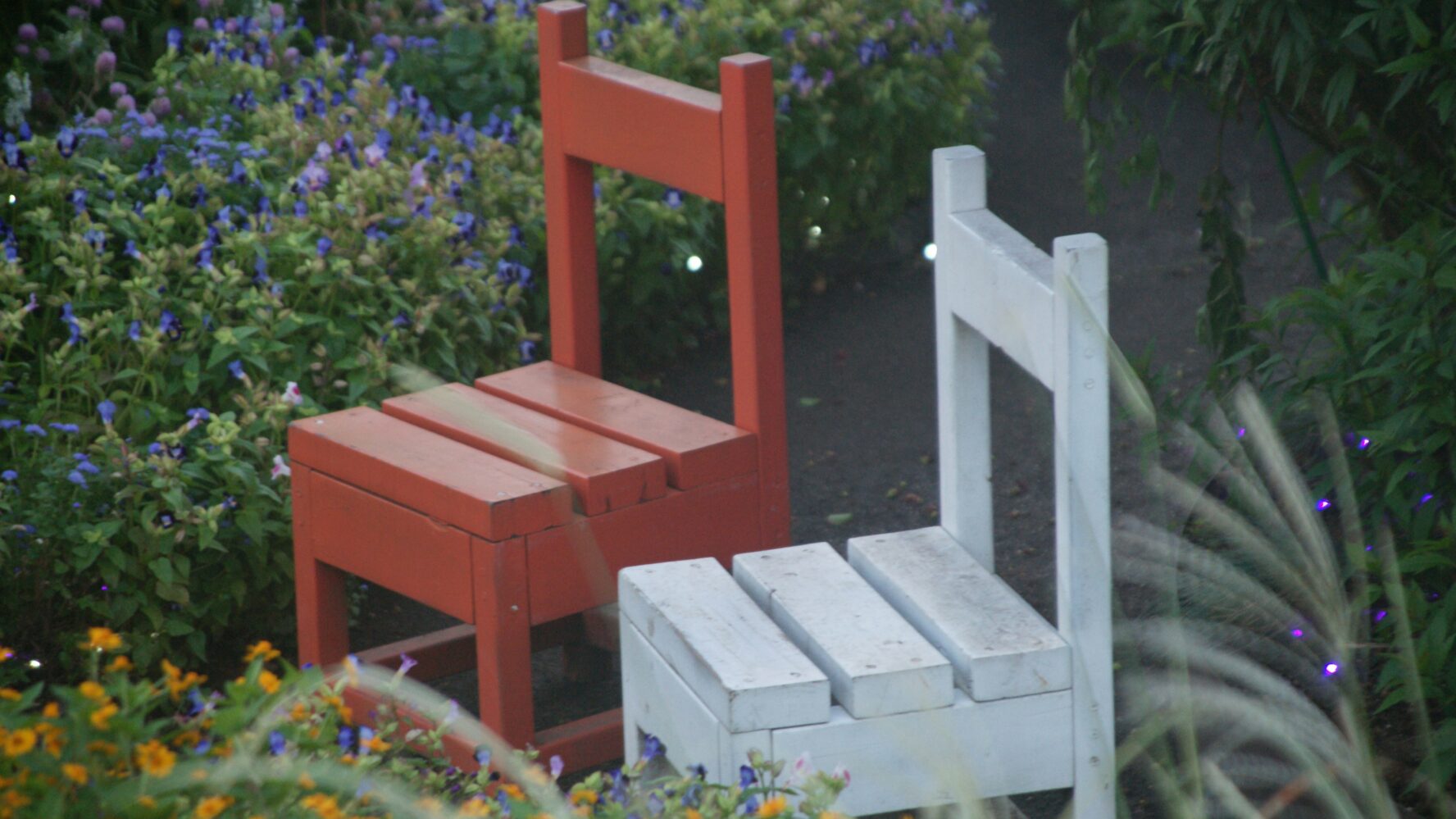 Two red and white wooden chairs on a garden path