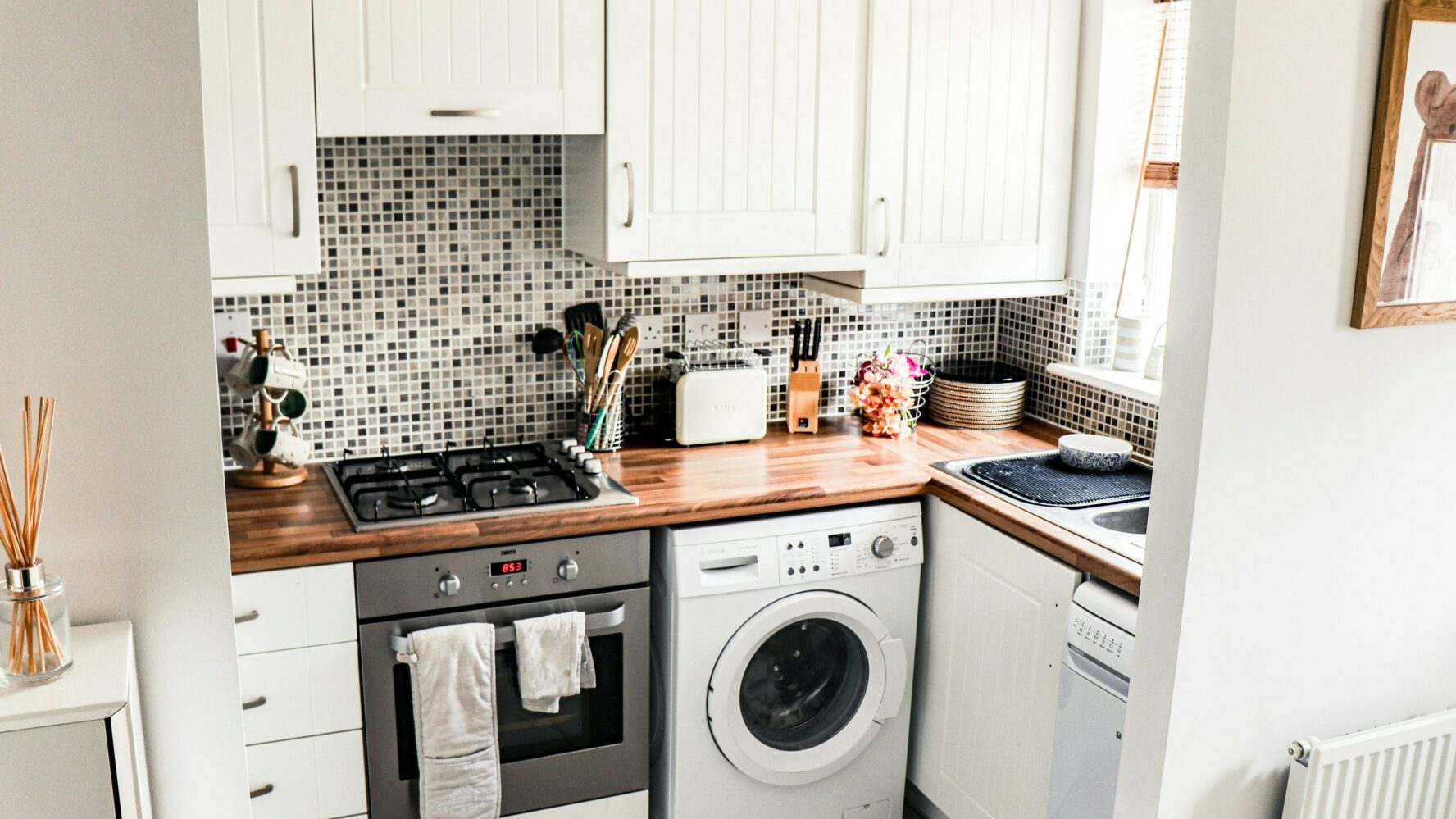 Image of a kitchen and typical household appliances, like a washing machine and a toaster