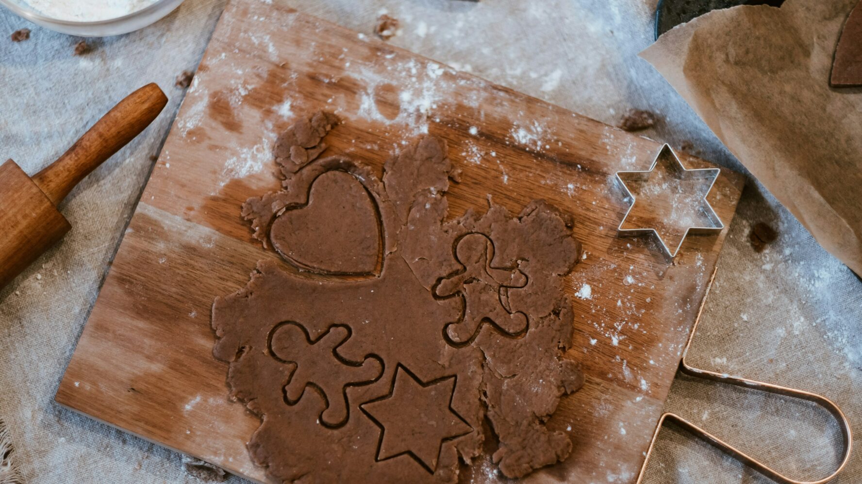 Christmas biscuits on a chopping board in gingerbread shapes, ready to be baked in the oven.