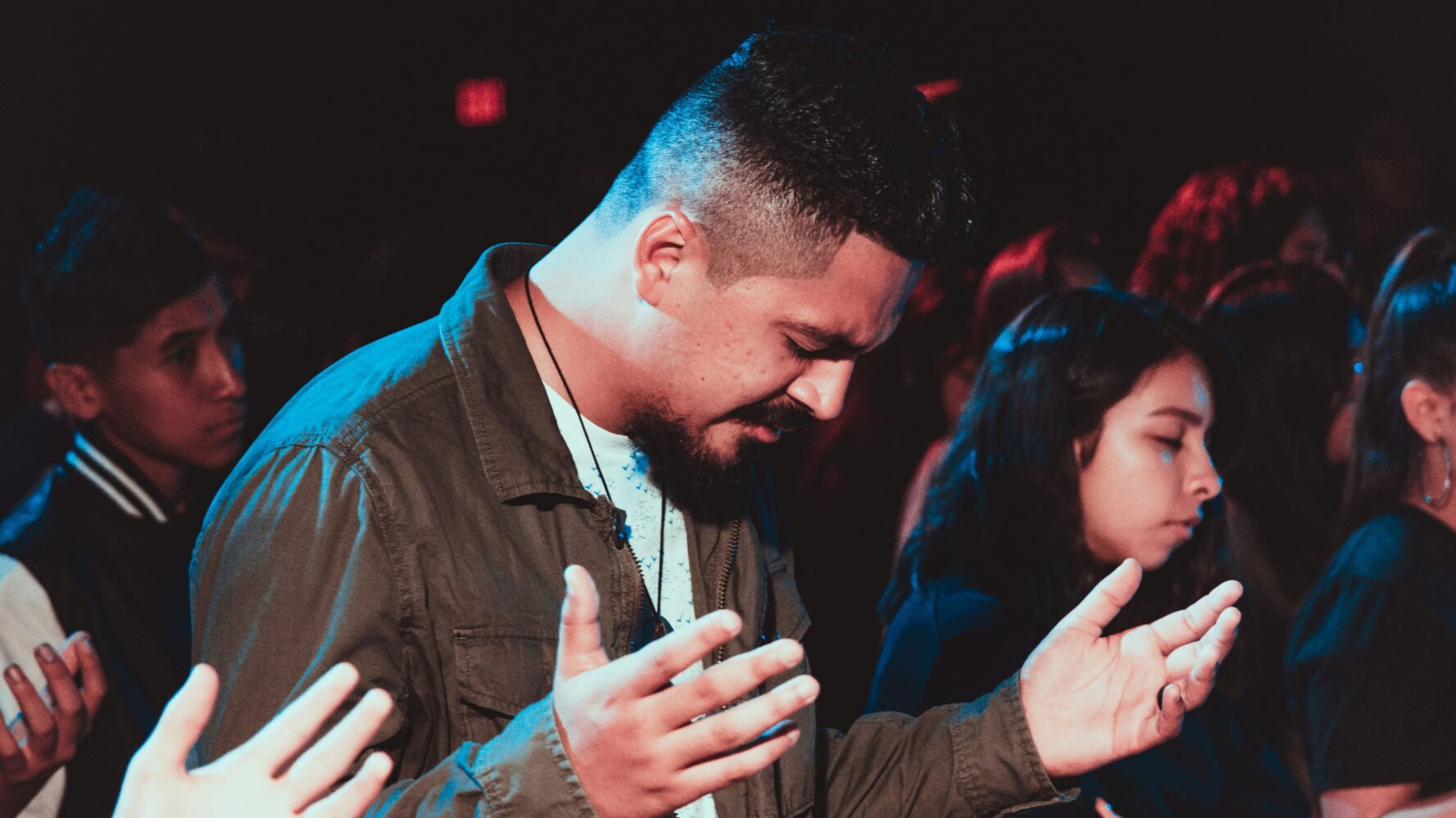 Man in his church with his head bowed and his hands out, praying