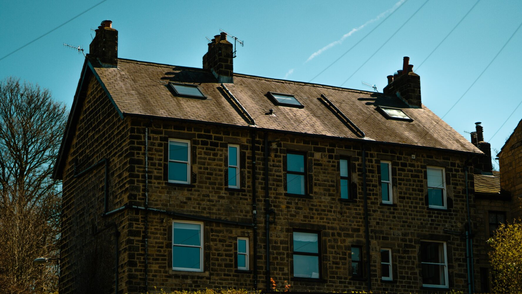 A row of three UK terraced houses under a blue sky