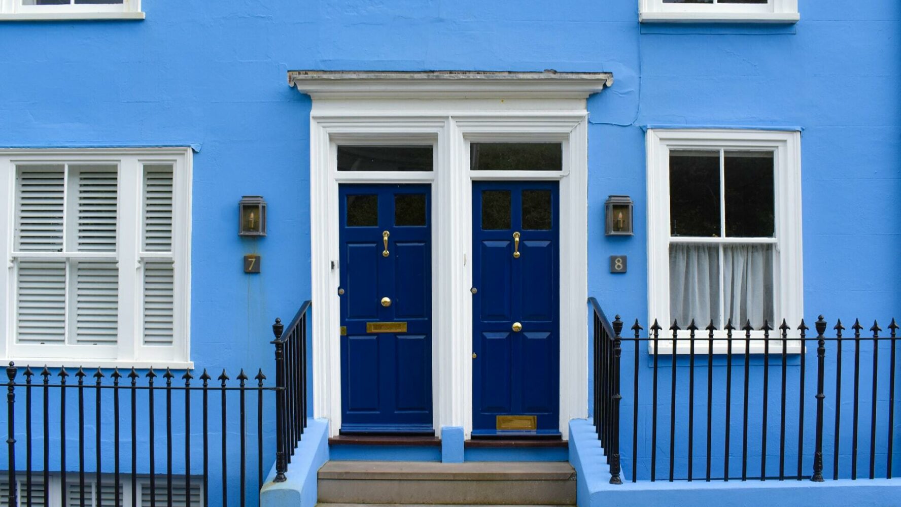 Two blue front doors with blue walls.