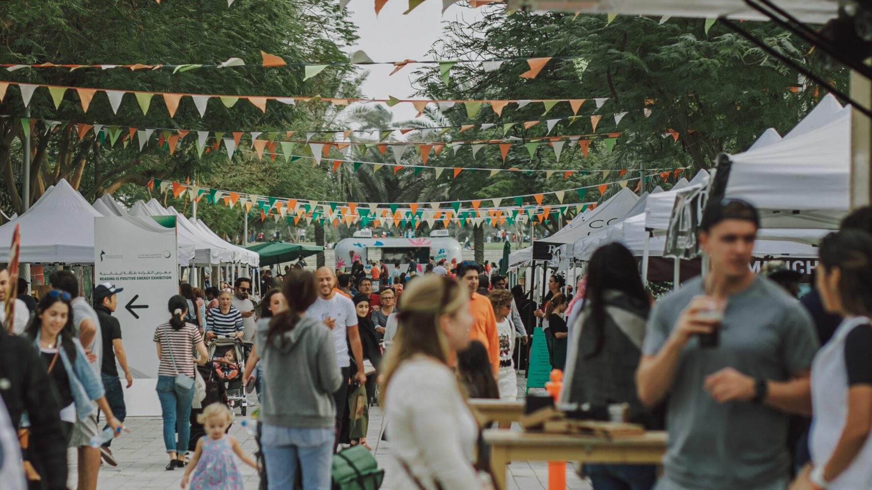 A summer outdoor event with people looking at different stalls.