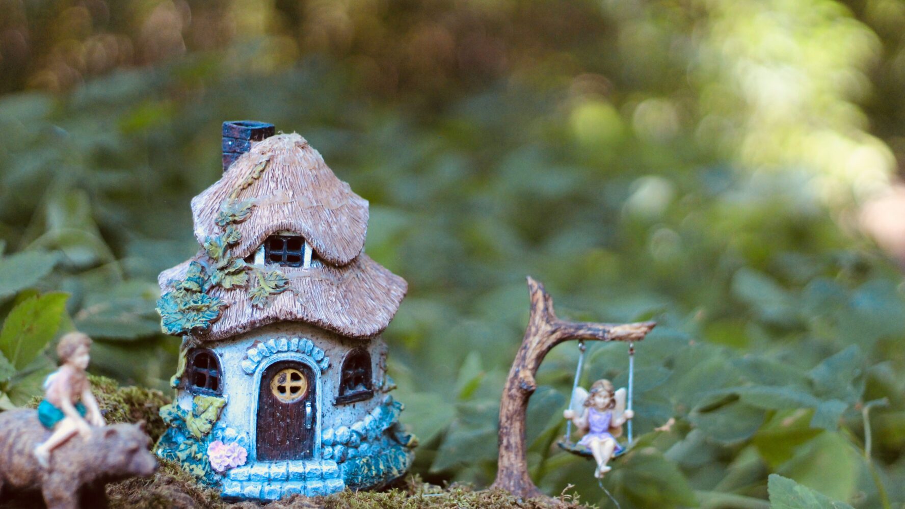 Blue fairy house and fairy figurine in a garden