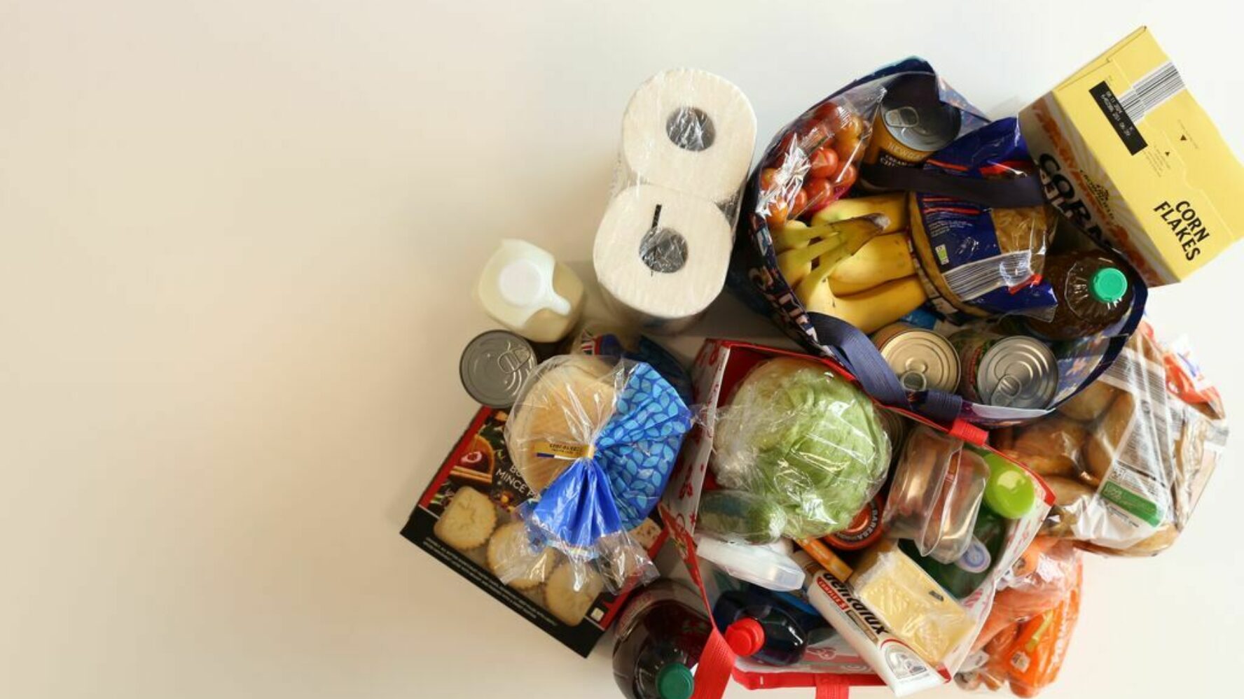 Shopping bags filled with essentials such as bananas, cereal, kitchen roll, bagels, milk, salad, mince pies and toiletries.