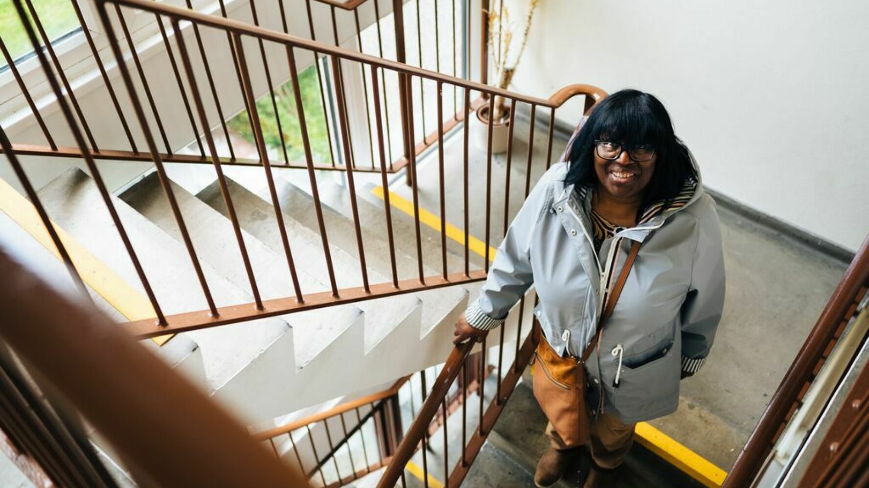 A woman smiles up at the camera as she goes up a flight of stairs