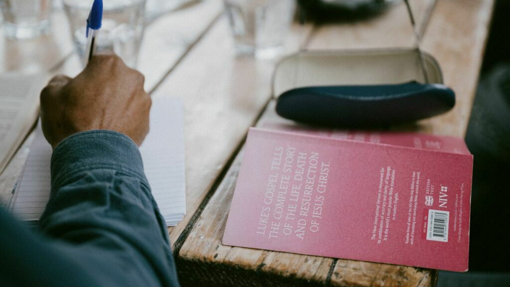 Image of a bible with a person writing a letter next to it