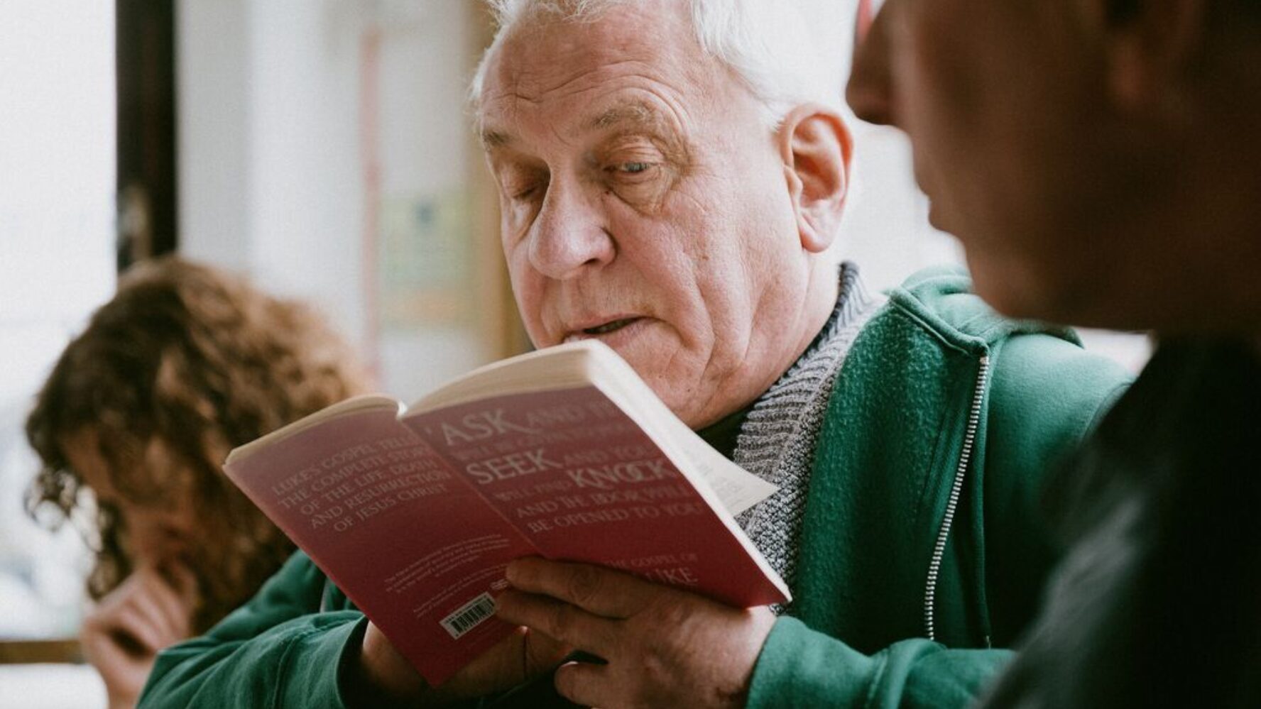 Image of an older gentleman at his church community group, reading the book of Luke
