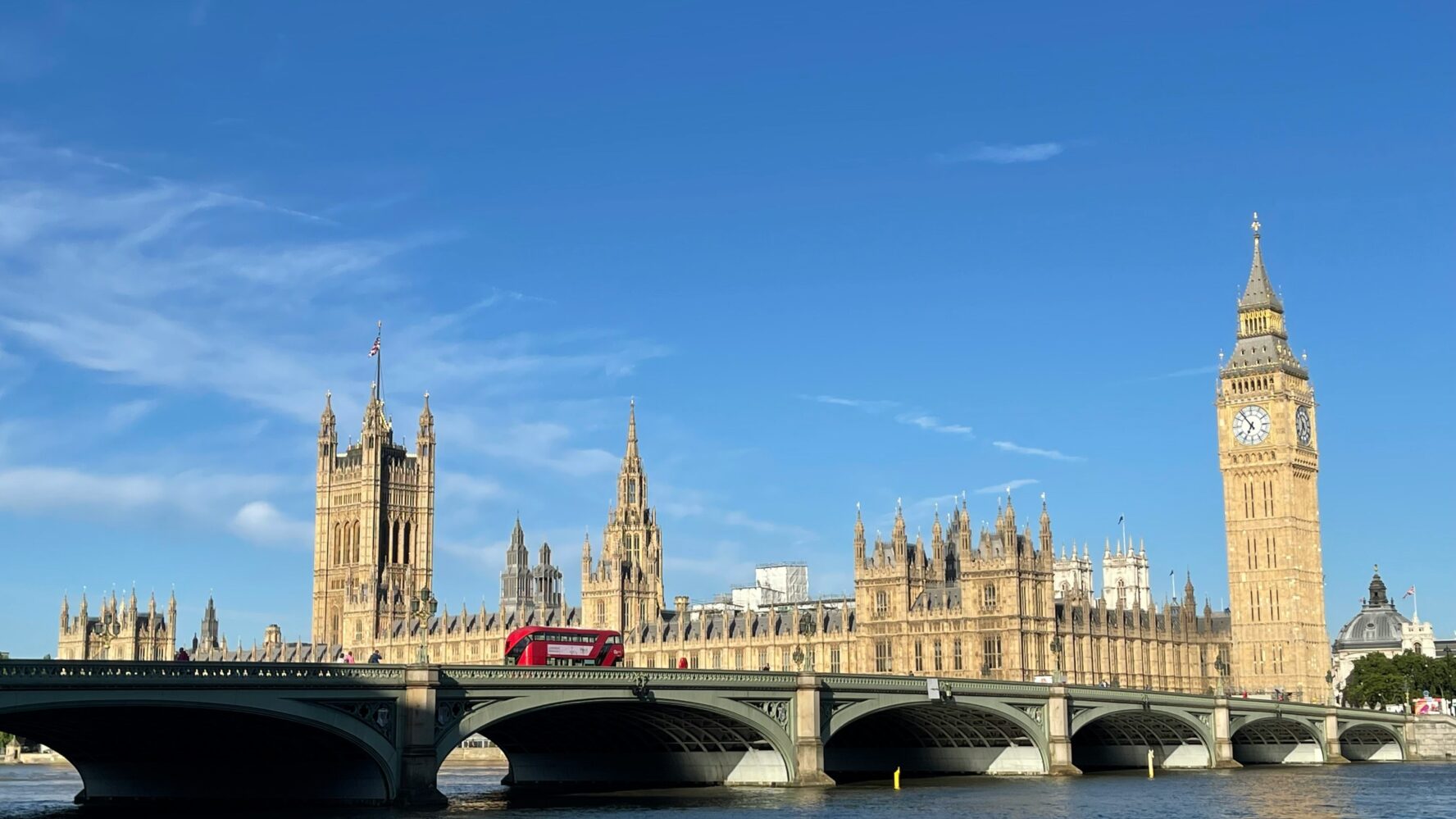 Westminster skyline and a London red bus on a sunny day with blue skies