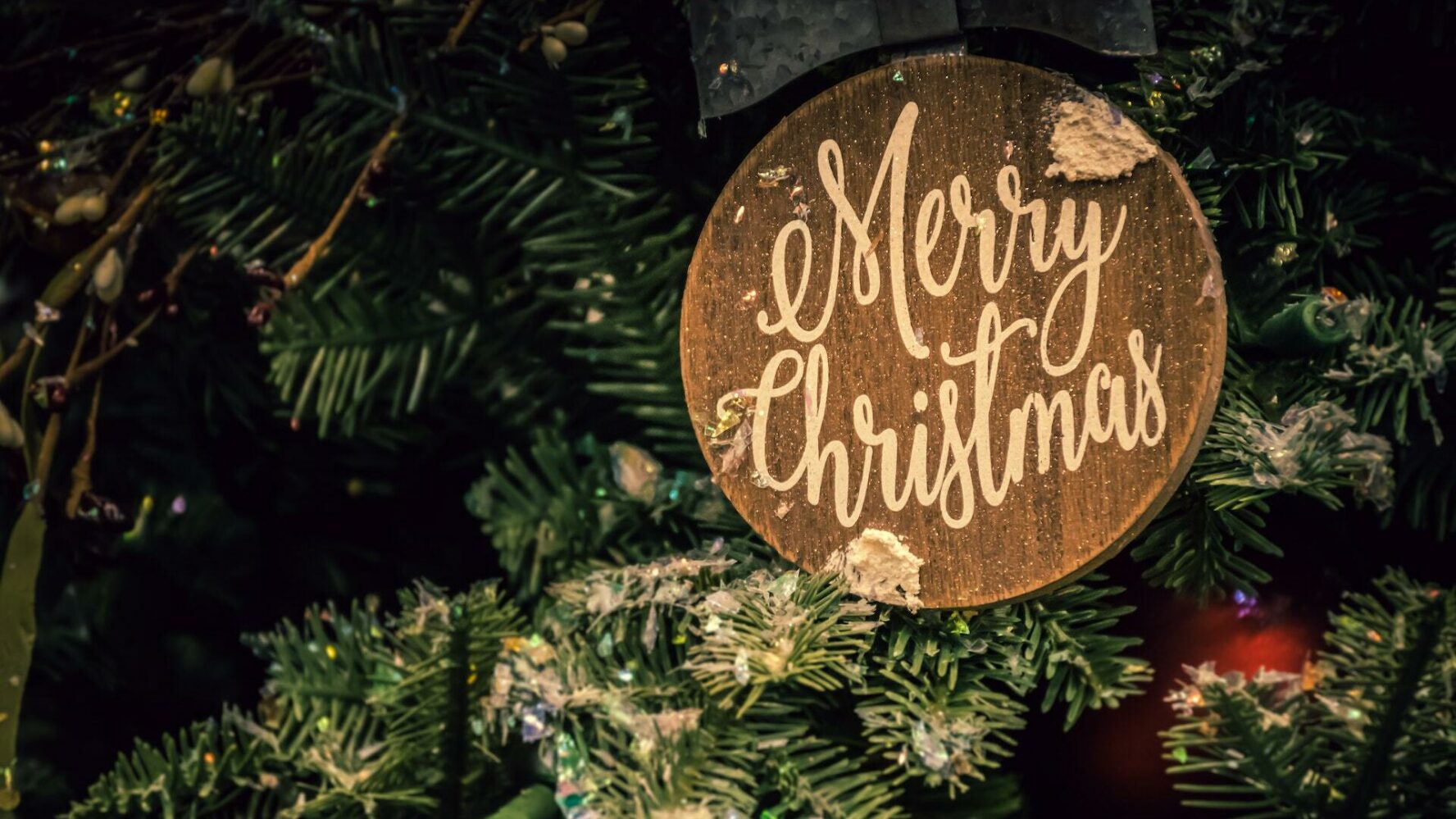 A round tree ornament features the words Merry Christmas