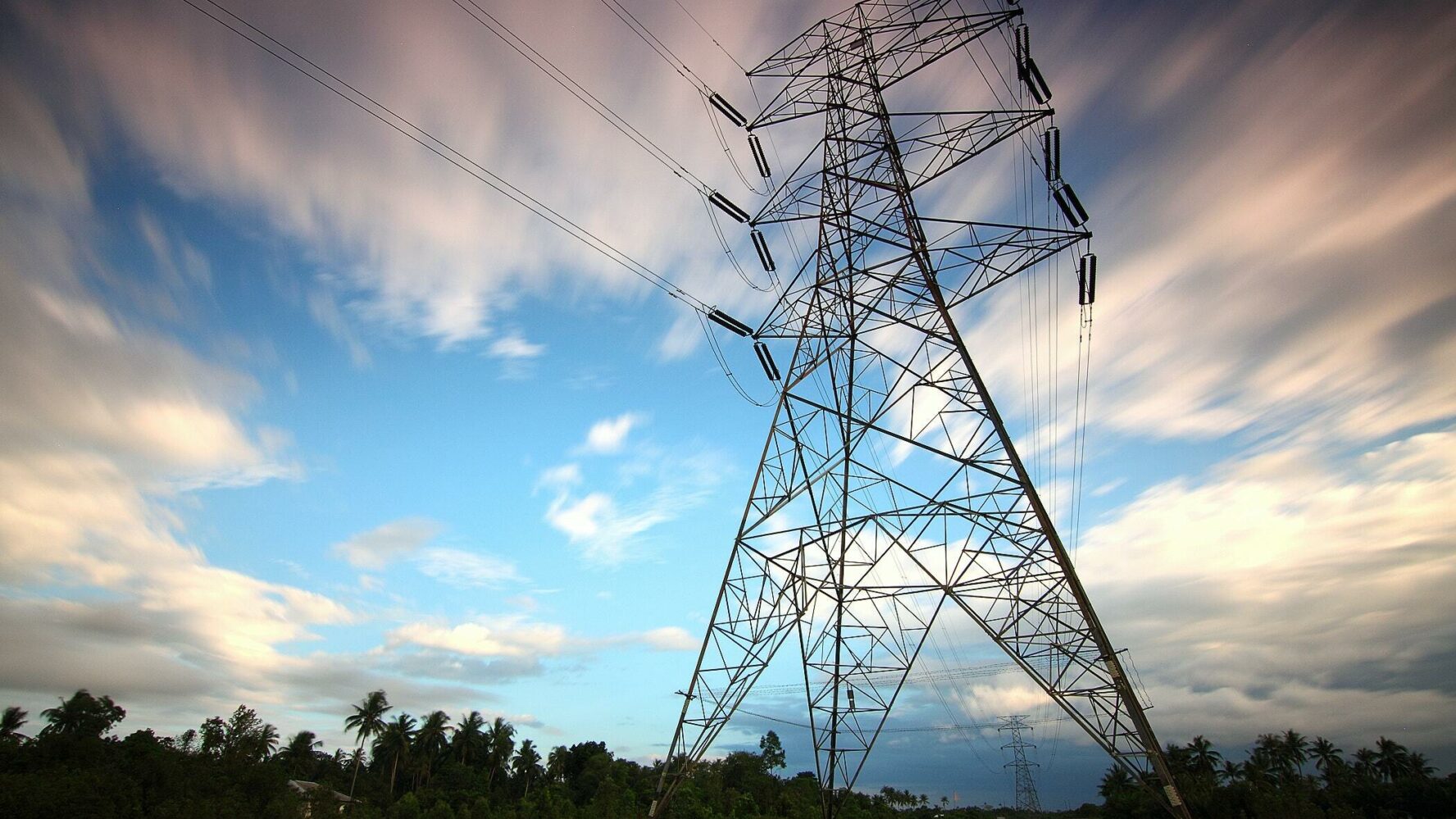 An electricity pylon in front of an atmospheric cloudy sky.