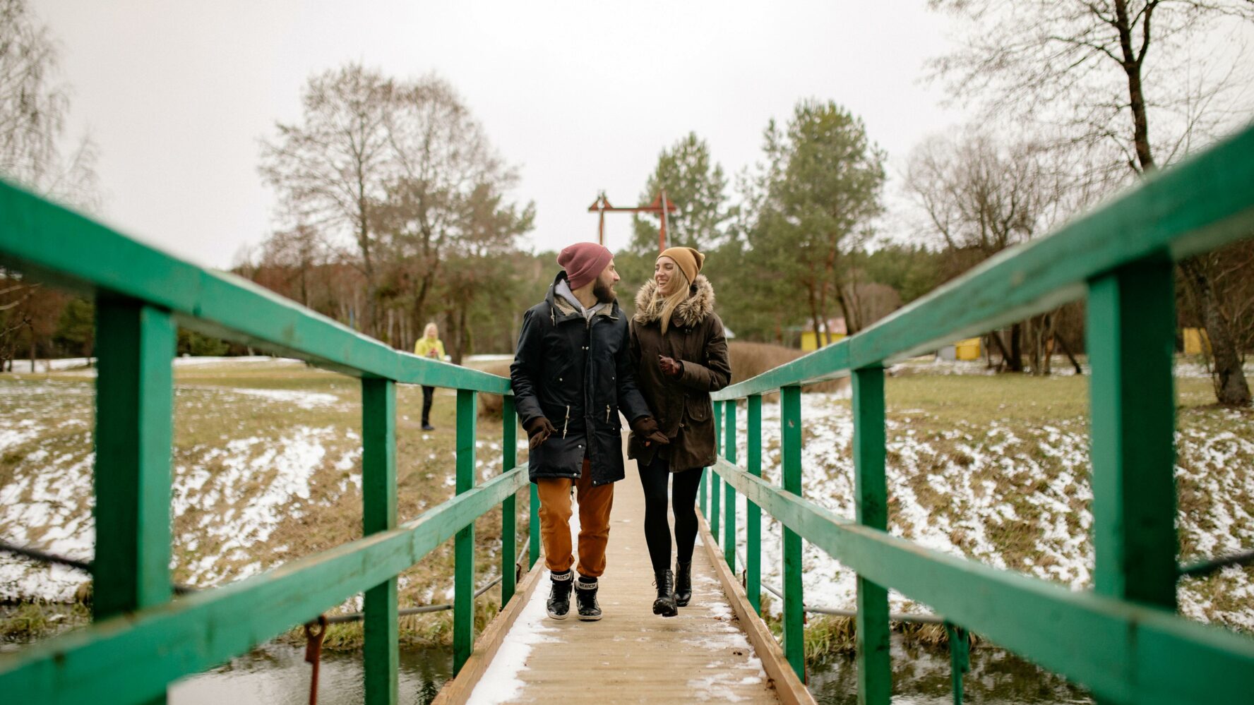 a couple walk across a park bridge