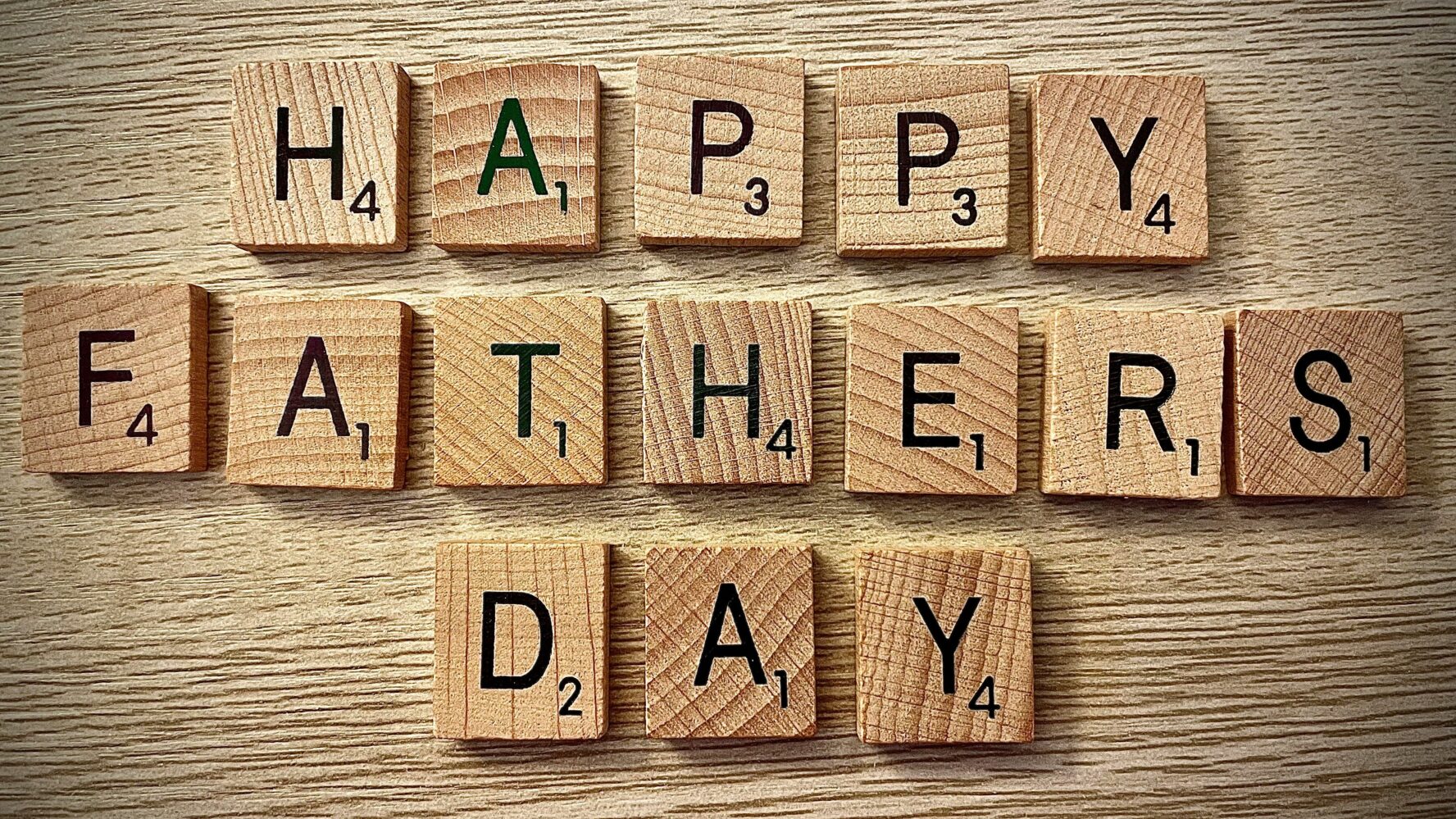 Image of scrabble letters on a table that read 'Happy Father's Day'