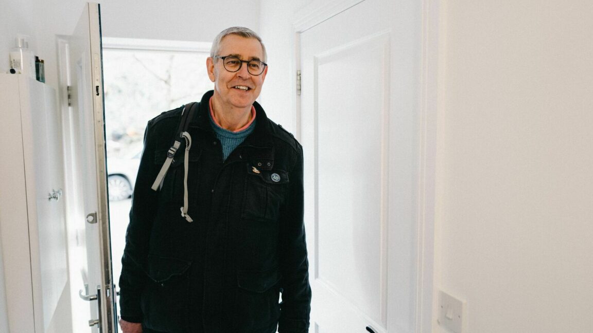 Debt coach Steve walking through the front door of a building. He is smiling and wearing a back pack