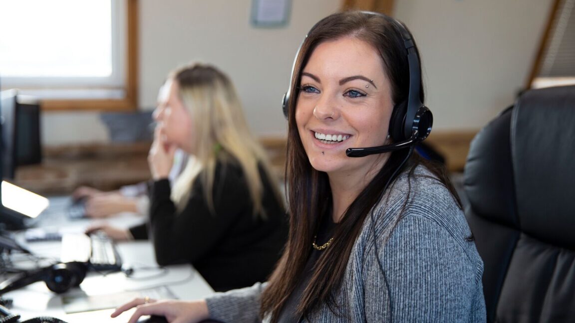 CAP worker, Kelsey, on the phone to a supporter and smiling