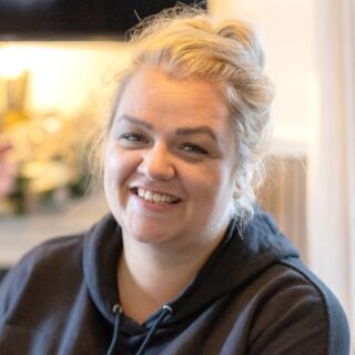 CAP client, Holly, sat in her living room, smiling at the camera