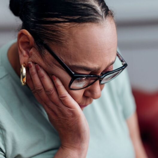 Close-up photo of CAP client, Sharon, looking down with her hand placed on the side of her face.