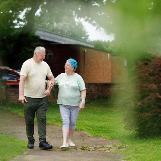 Bea, former CAP client with bright blue hair, and her husband Keith, walking hand in hand and smiling