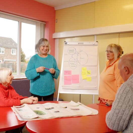 A local church receiving training from CAP to help find ways to help their local community. They are sat around a table writing down ideas on a whiteboard.