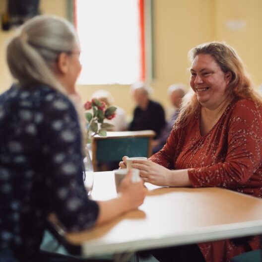 CAP client, Wendy, sat at a table in her local church hall and smiling