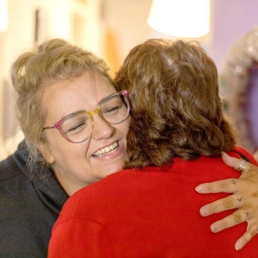 CAP client, Holly, hugging her CAP debt coach, Irene, in her home