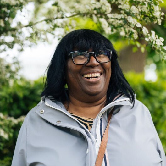 CAP client, Melinda, stood outside in a garden, looking up and smiling