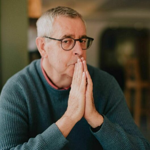 Debt coach steve looking into the camera, with his hands raised to his mouth in a praying position