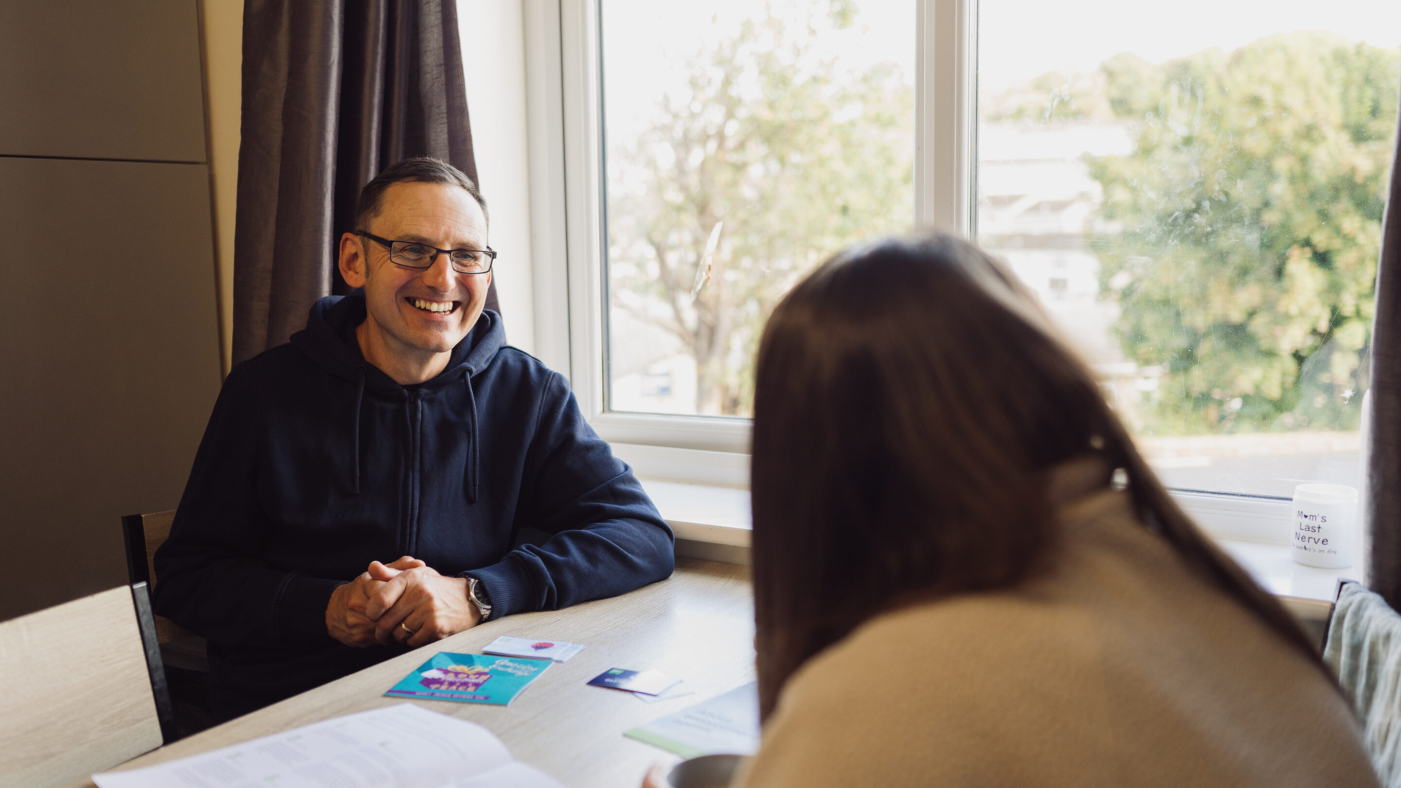 CAP debt coach speaking with CAP client, Jade, smiling and talking through her debt help options in her home