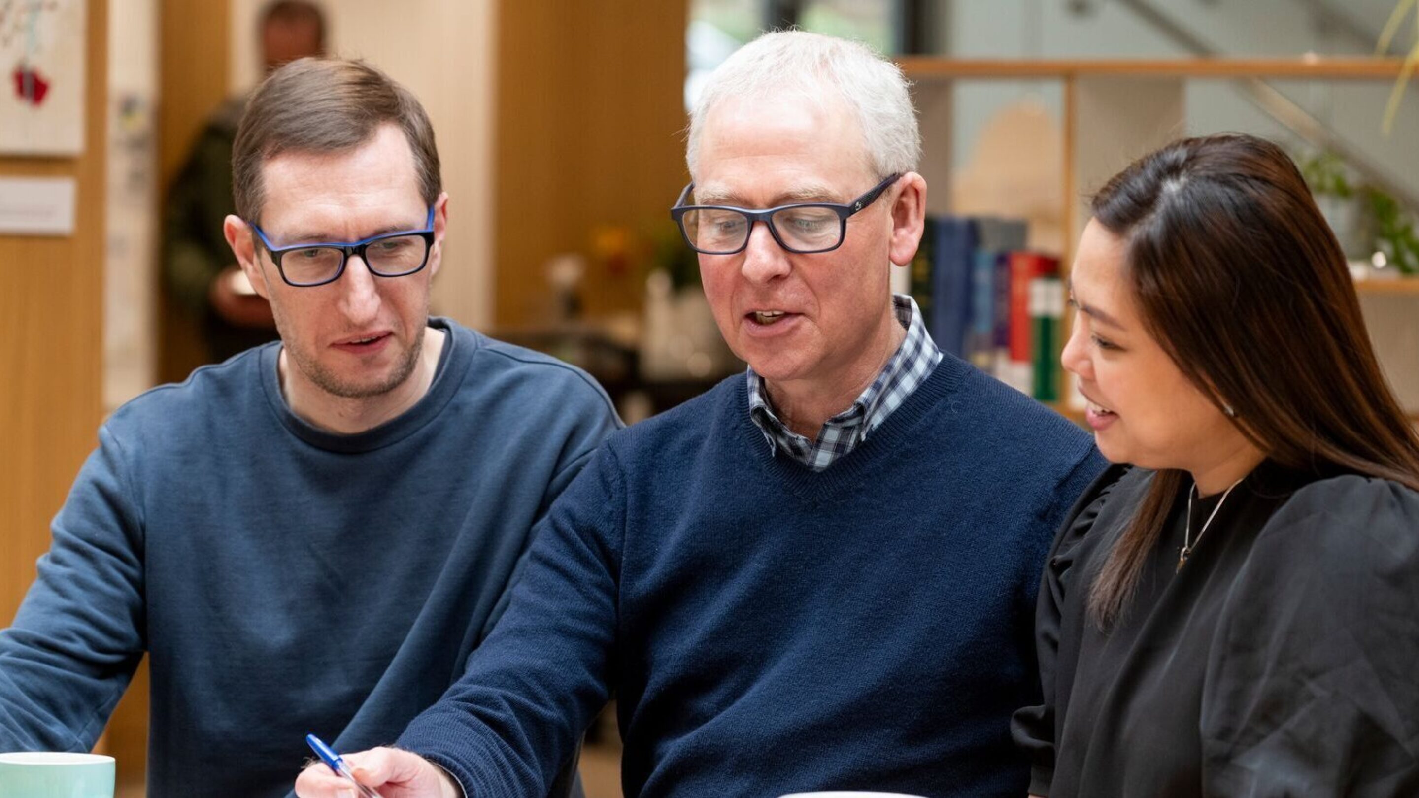 Two job club attendees, Tim and Sue, sat at a table speaking with their job club coach.