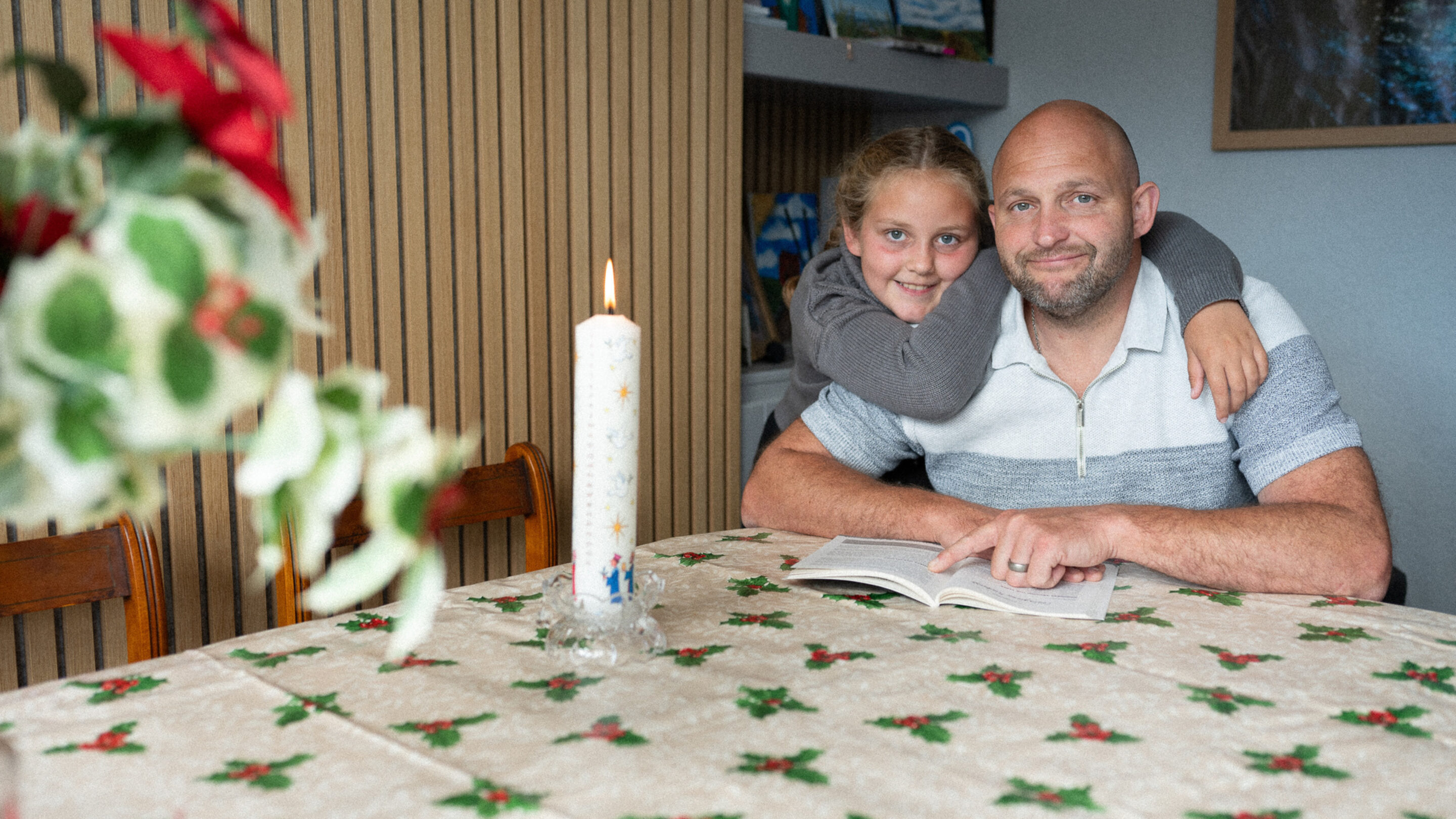 A father and daughter sat at a table reading from a bible