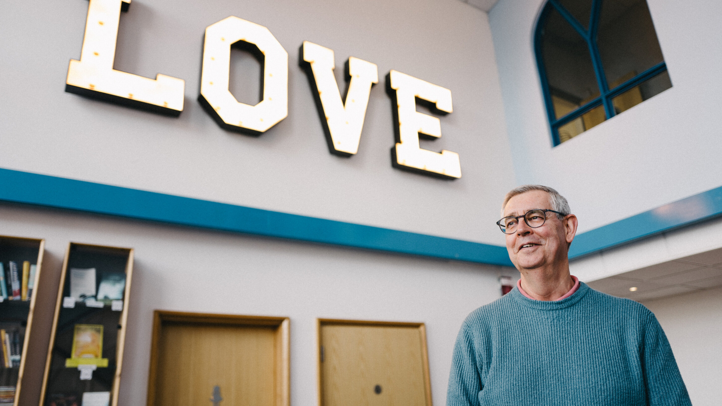 debt coach at a church with a sign that says love behind him