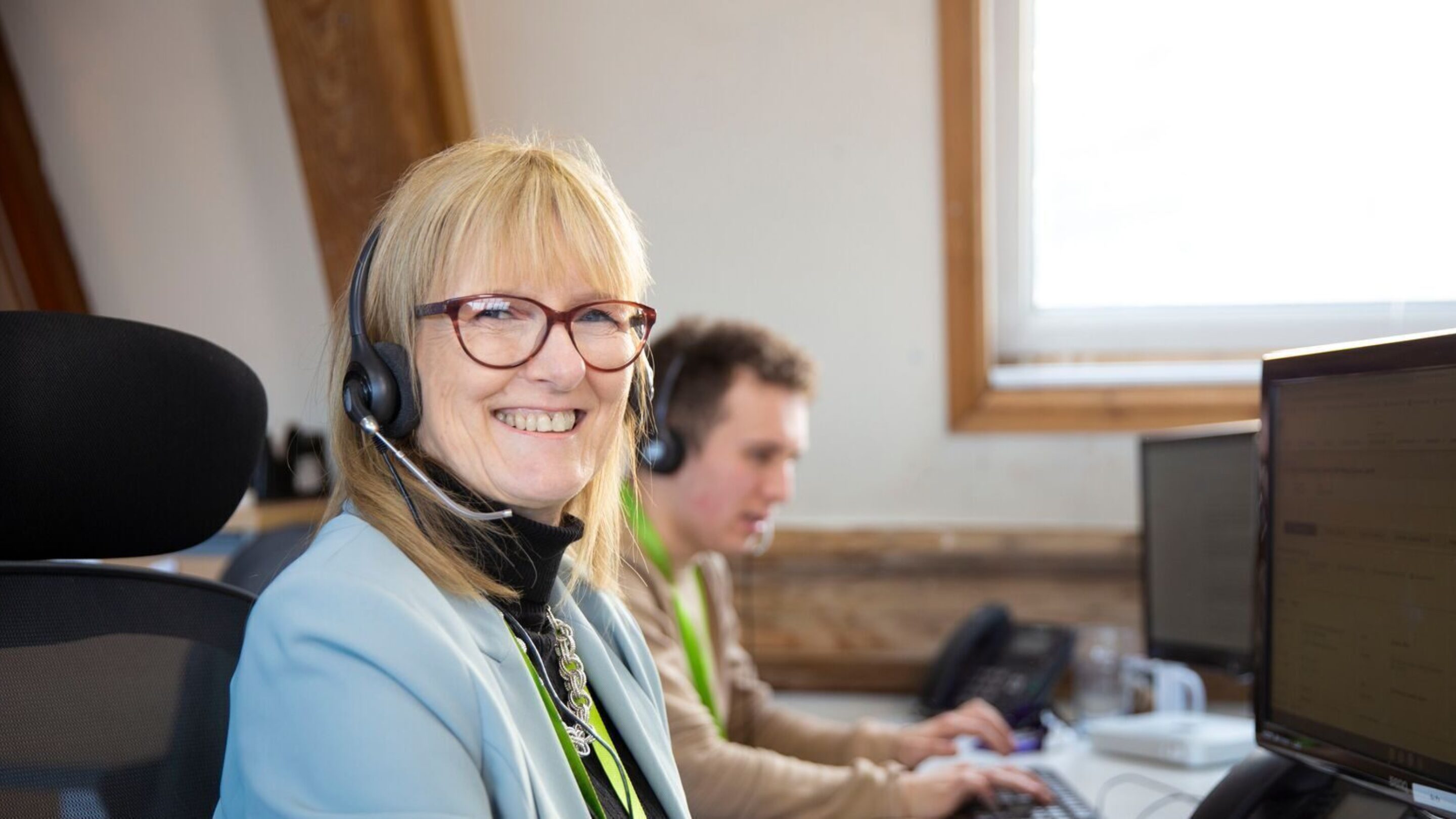 Image of CAP staff member, Sue, wearing a headset in Head Office and smiling at the camera