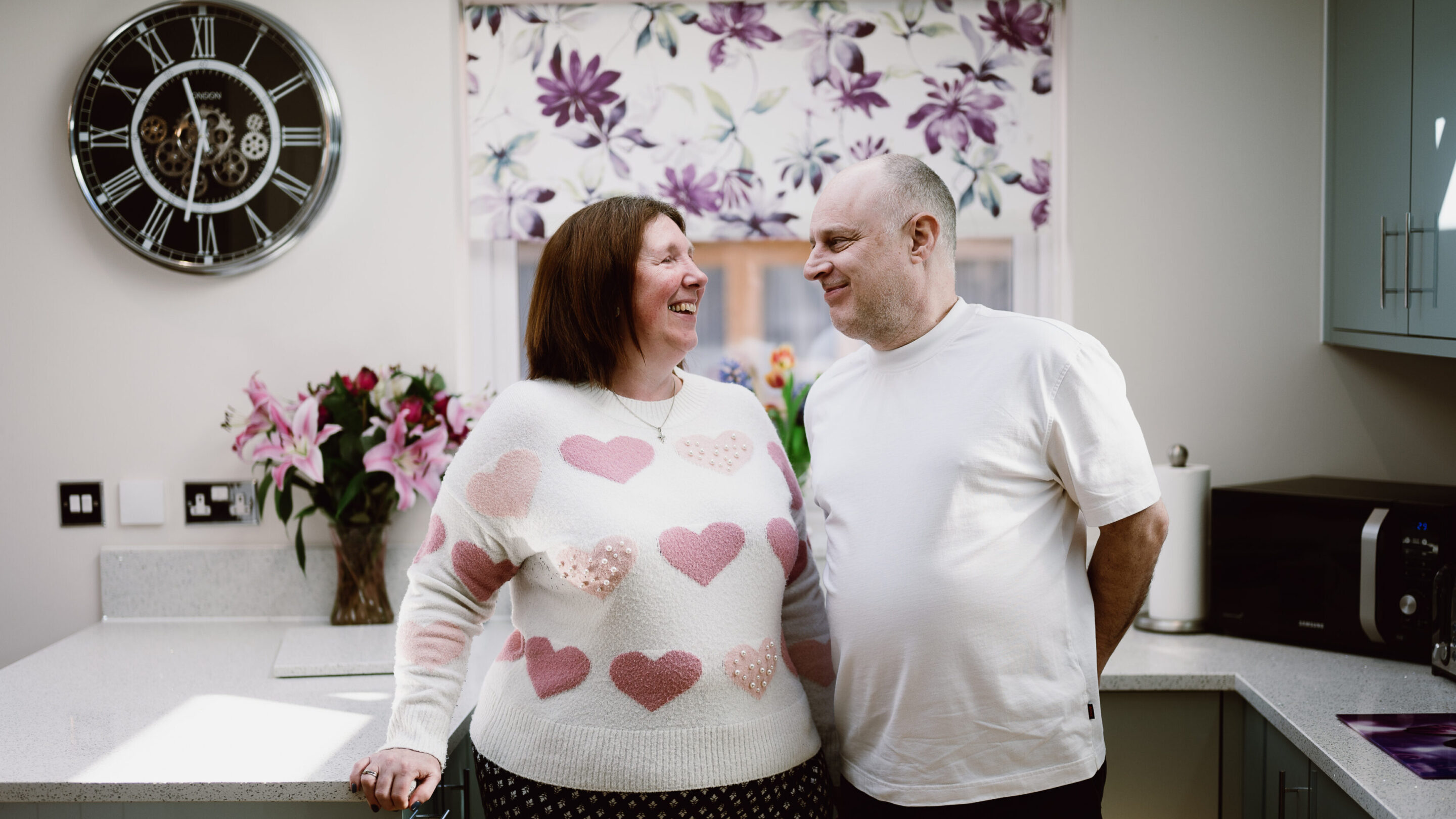 CAP client Angela, stood smiling next to her husband in their kitchen