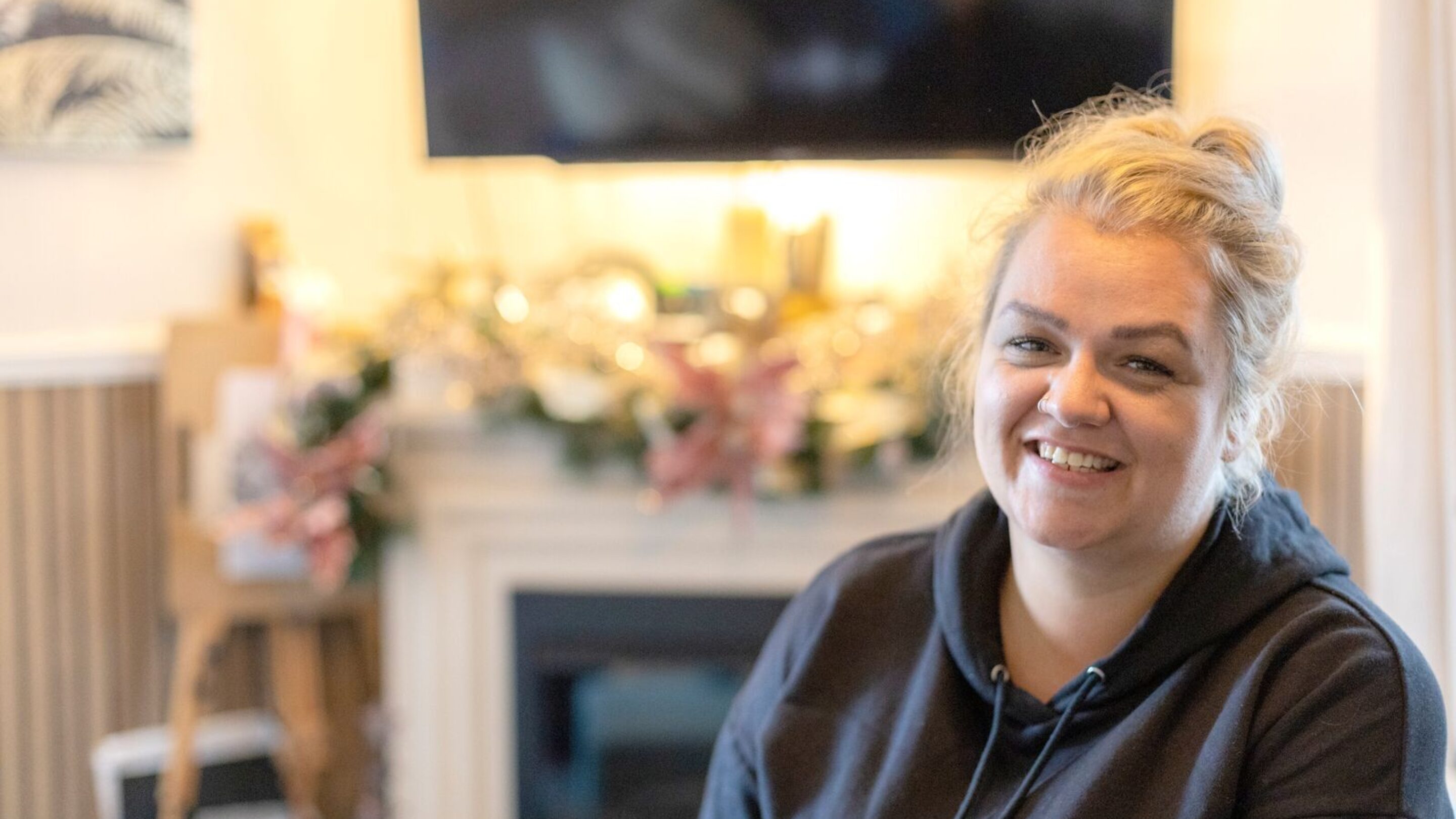 CAP client, Holly, sat in her living room, smiling at the camera