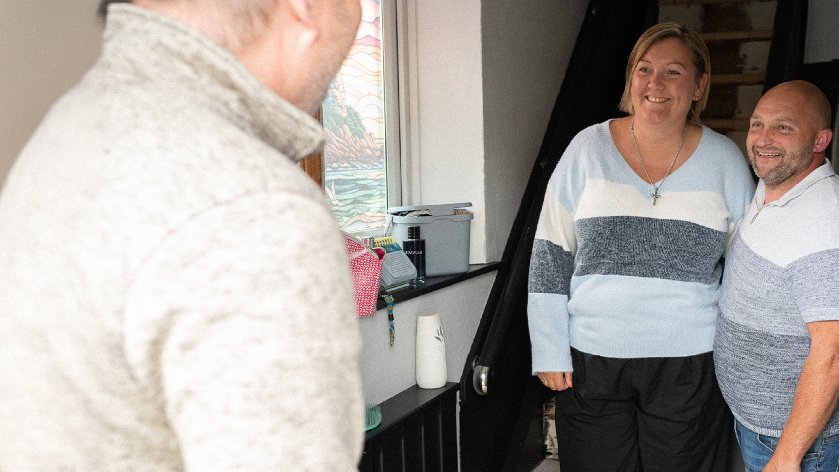 Paul and Sam, now debt free, smiling opening the door to their debt coach from their local church