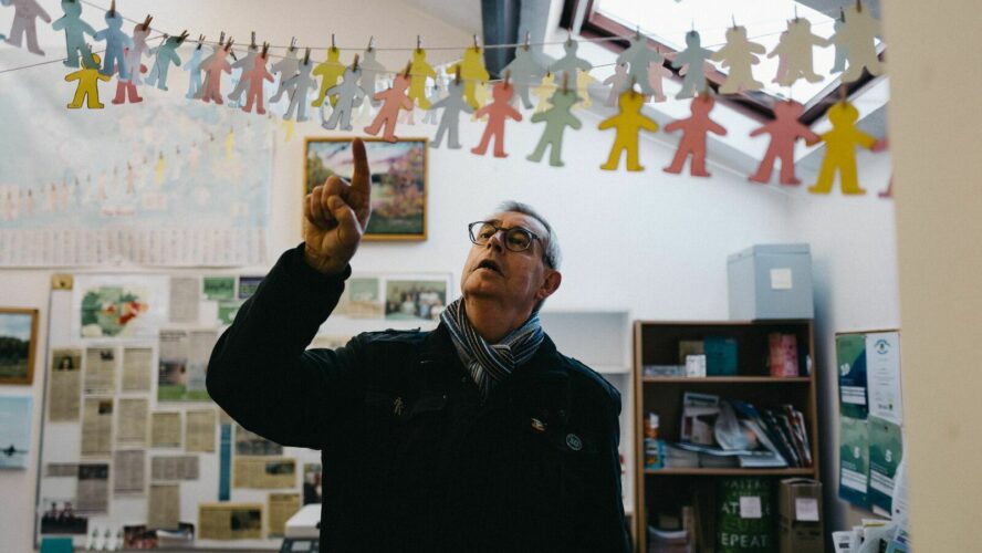 Debt coach Steve, pointing at a hanging display of small, paper cutouts of people