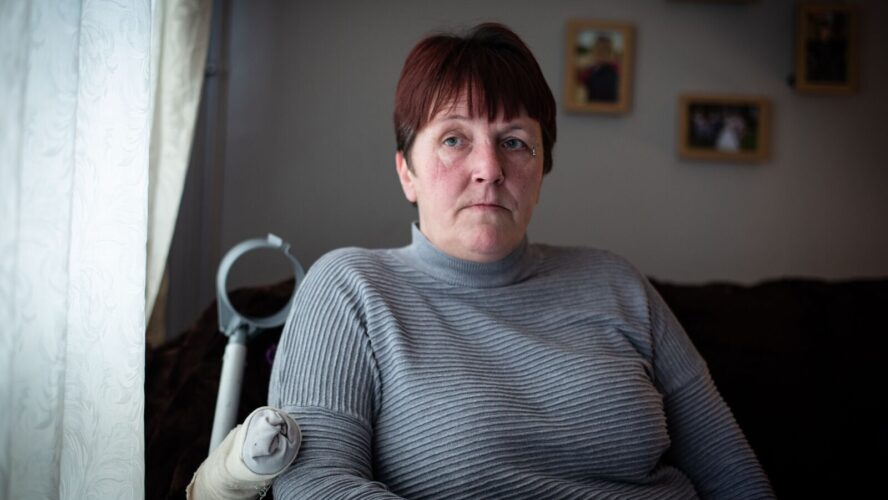 CAP client Tina sat in her living room looking outside, sat next to her crutch