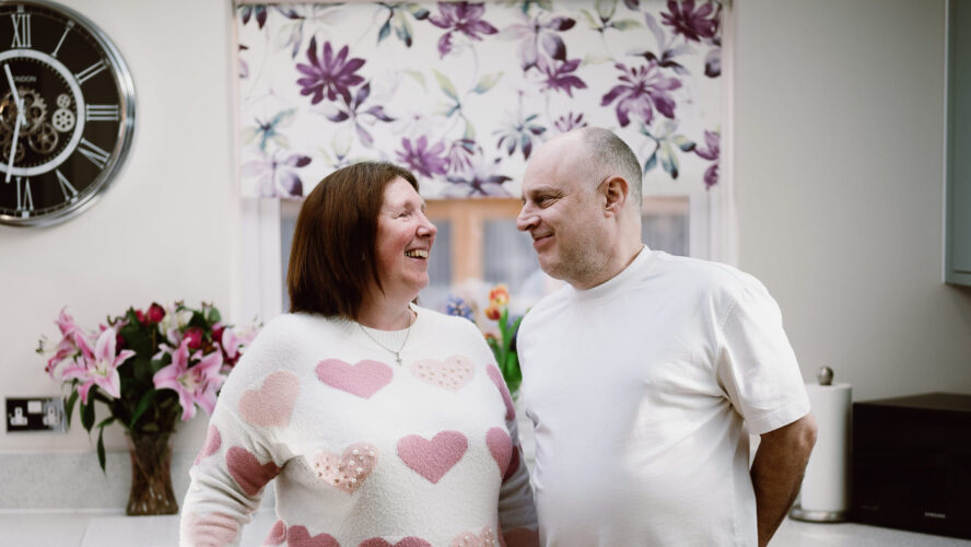 CAP client Angela, stood smiling next to her husband in their kitchen