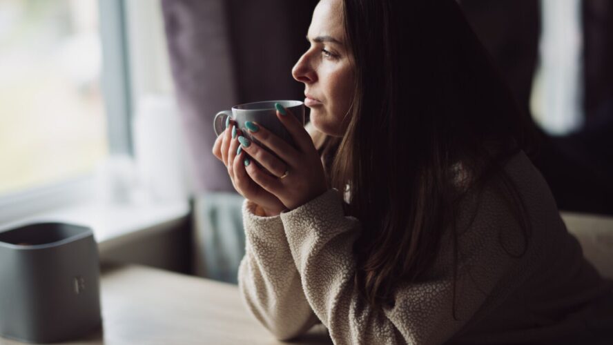 CAP client, Jade, sat at her kitchen table, holding a cup of tea and looking out of her window.