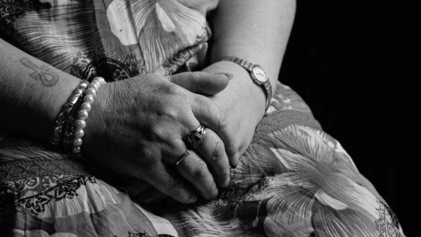 Close up black-and-white photo of a middle aged person's hands on their lap.