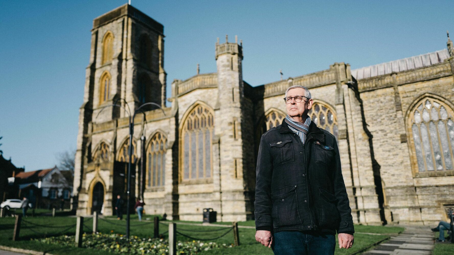 Debt coach Steve stood outside of a church building, looking into the distance