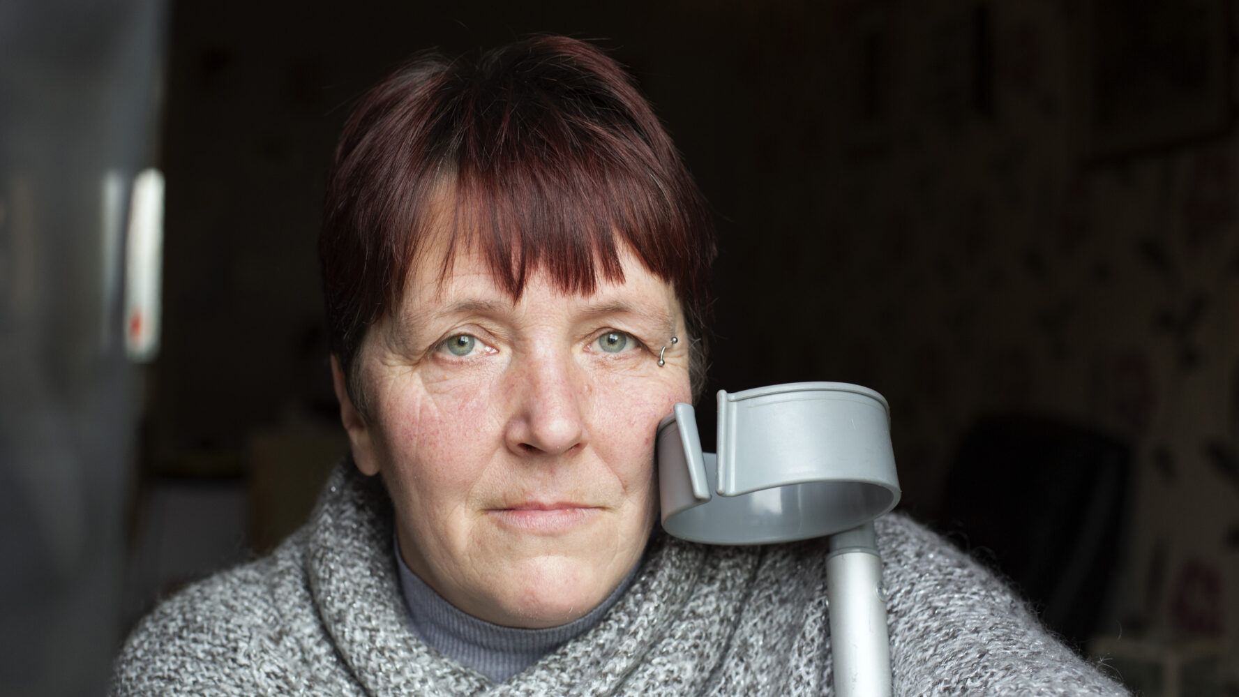 Tina, ex CAP client, looks into the camera with her crutch next to her
