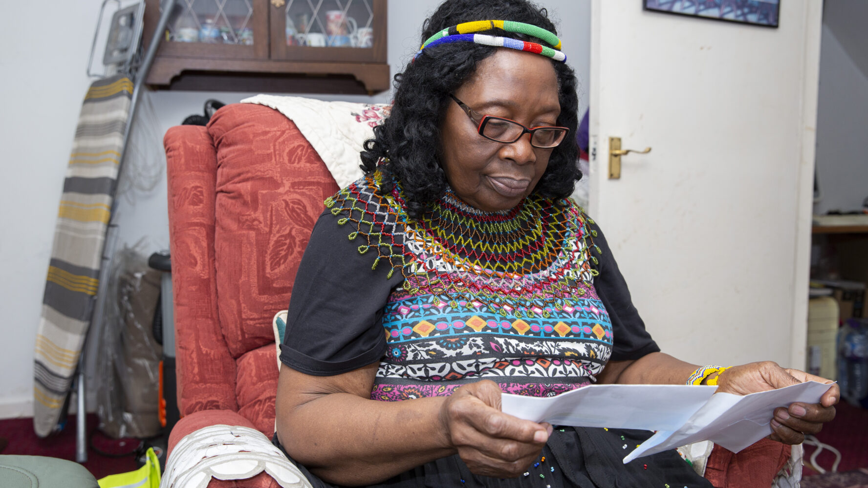 Lady sat on her living room chair, opening a letter