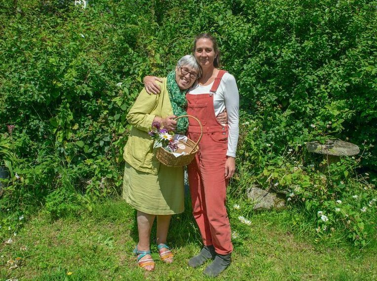 Image showing two smiling women stood in a garden, one is holding a basket