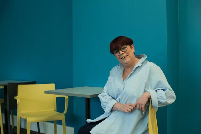 CAP client smiling and sat on a yellow chair against a blue background